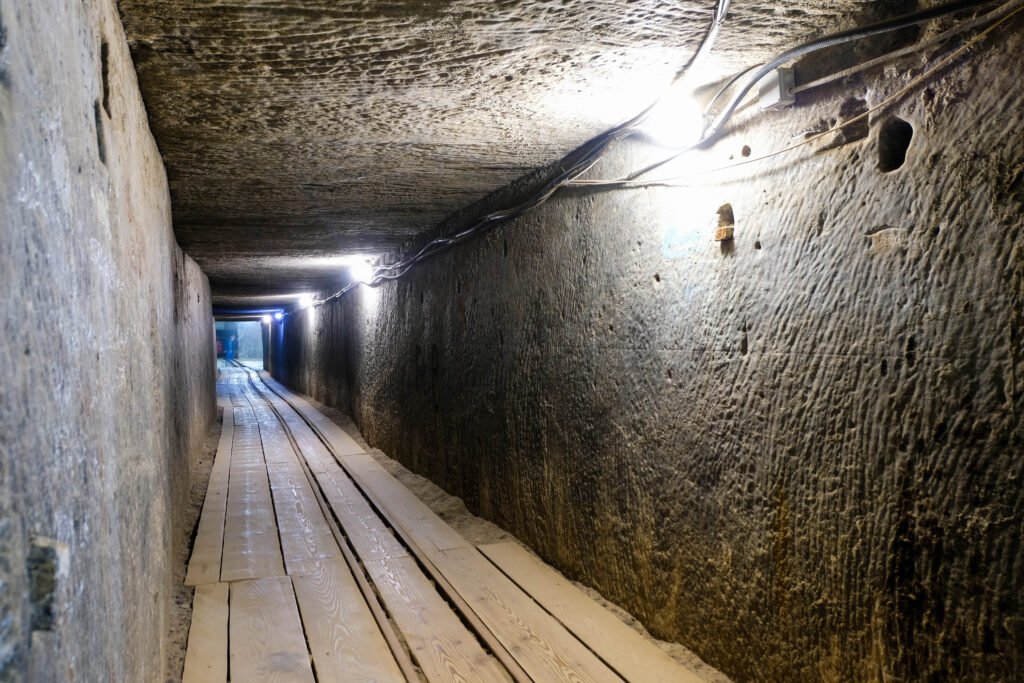 Moisture-damaged tunnel with wet concrete walls and lighting, showing signs of water seepage and leakage issues.
