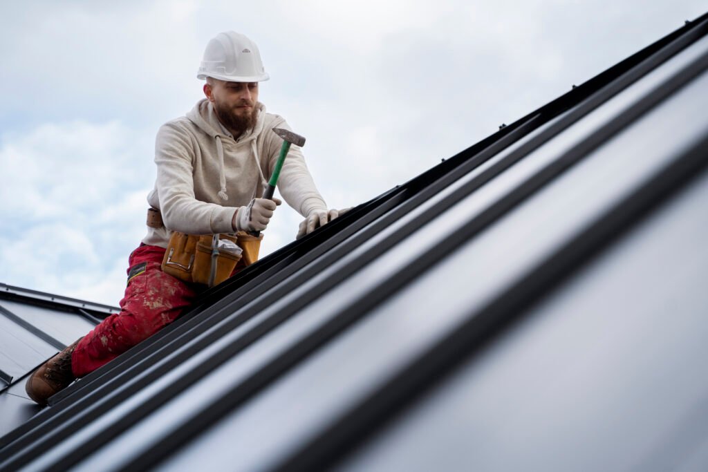 Worker applying roof waterproofing on a sloped roof to stop leaks and weather damage.