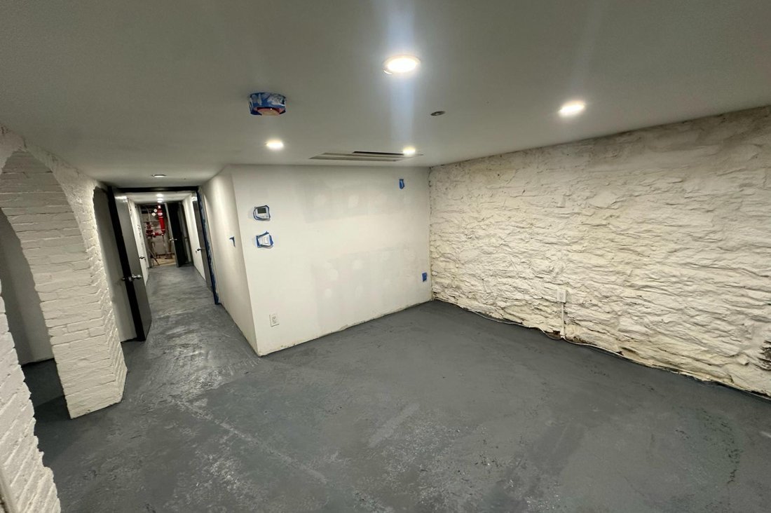 NYC basement with a stone foundation wall and sealed concrete floor after waterproofing